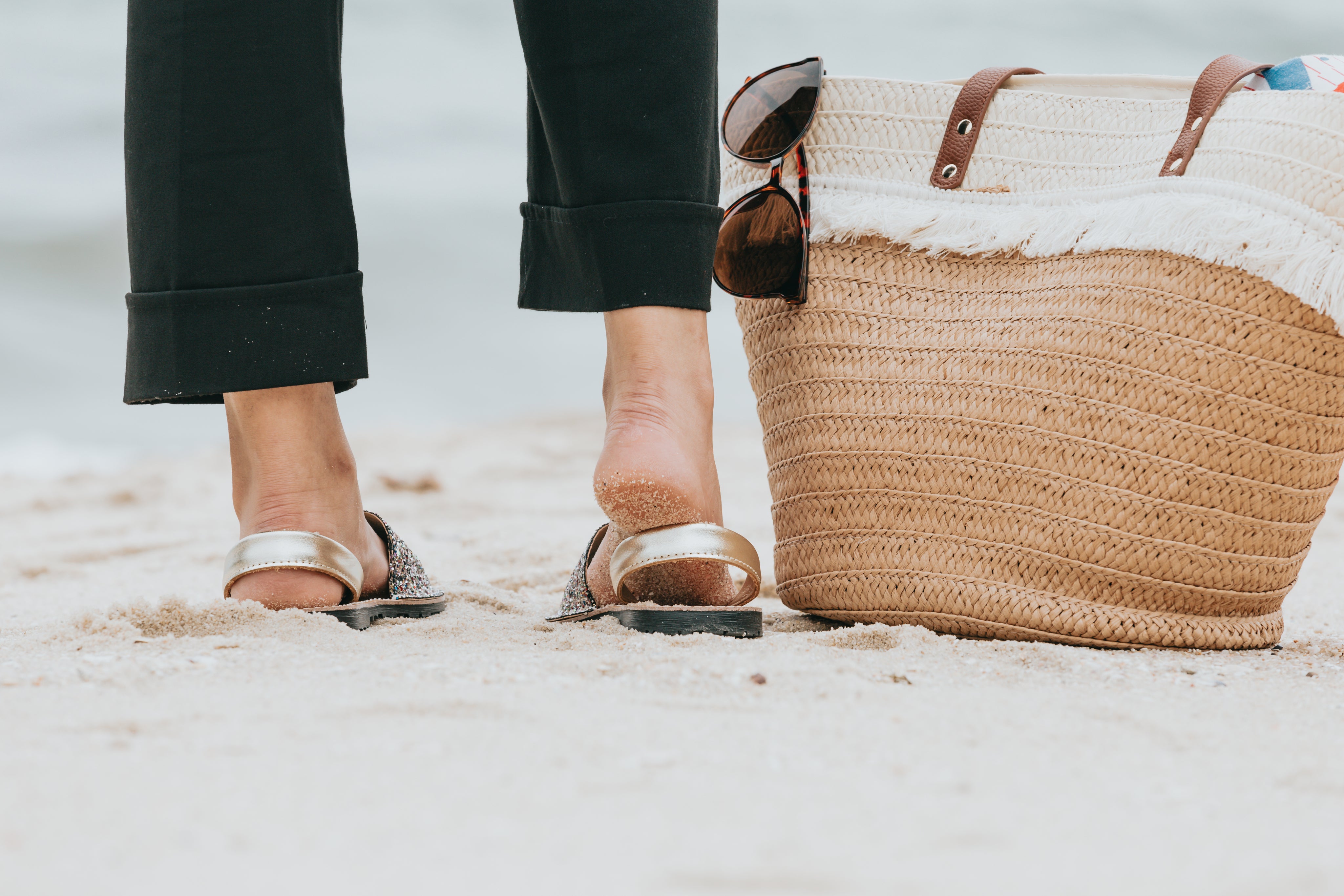 photo-of-a-legs-standing-on-a-sandy-beach-next-to-a-beach-bag.jpg
